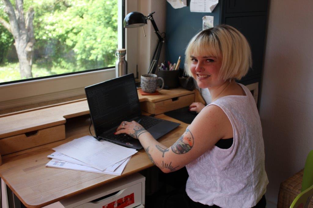 am Laptop arbeitende Studentin, lächelt